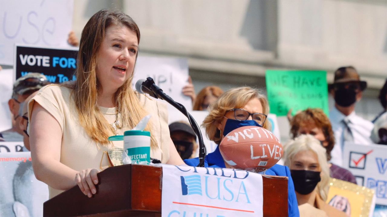a woman speaking into a microphone at a rally